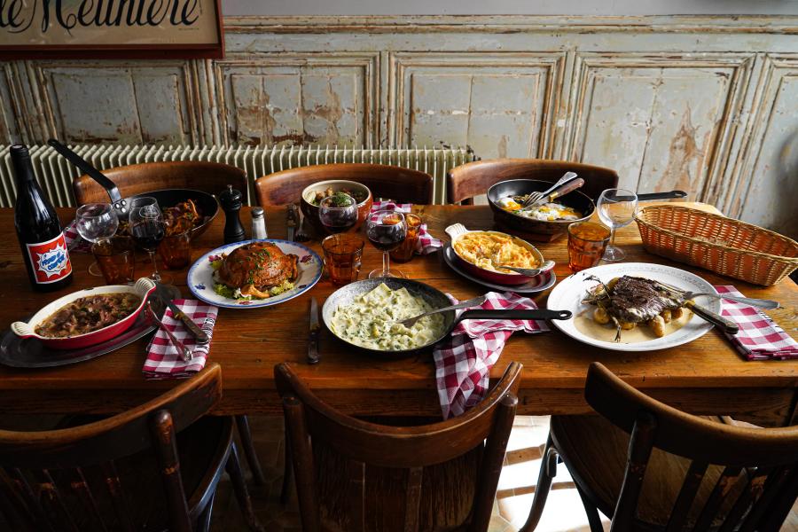 Table garnie de spécialités lyonnaises dans l’ambiance traditionnelle d’un bouchon lyonnais.