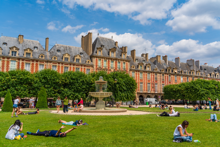 Visiteurs profitant des pelouses de la place des Vosges à Paris.