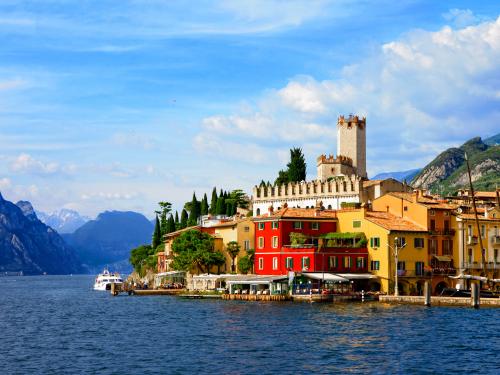 Vue du lac de Garde avec ses maisons colorées, son front de lac animé et les montagnes des Alpes italiennes.